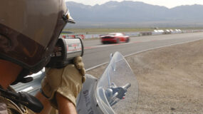 A cop using a detector to see how fast a red car is moving